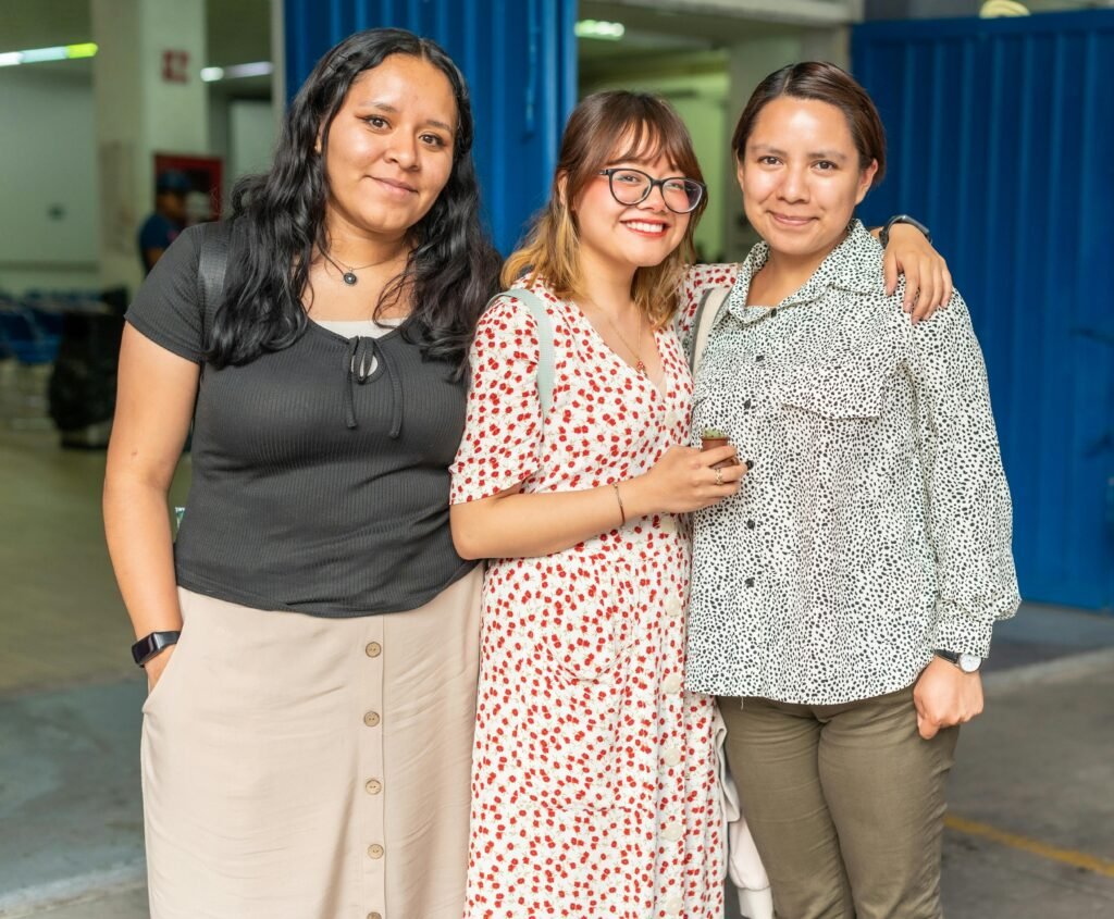 Three friends posing happily together indoors, showcasing friendship and joy.